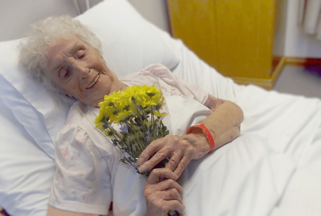woman in hospital bed holding flowers