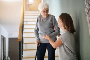 women helping elderly woman down the stairs